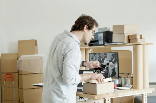 Entrepreneur packaging shoes for online orders in a small workspace with boxes and shipping supplies, representing the early stages of starting an online business.