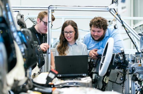 Employees using laptop for collaboration, showing benefits of HR software in companies.